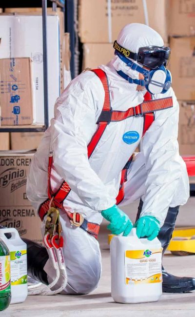 Industrial worker in protective gear handling chemicals in a warehouse environment.